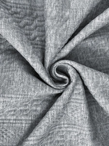 Détail macro du tricot jacquard gris montrant la texture douce et le tissage premium
