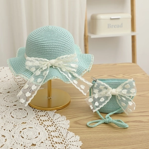 Detail of mint green straw sun hat and matching bag with lace bow for girls