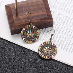 Detail of bohemian bronze round earrings with colorful vintage oil drip floral patterns