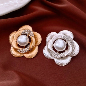Detail of camellia flower brooch with pearl center and rhinestones on silk fabric