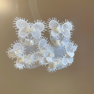 Detailed macro view of white handmade lace and shell petals in a butterfly earring design