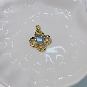 Elegant gold four-leaf clover pendant with inset zircons on a white ceramic dish