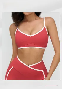Detail of red sports bra with white contrast piping and crossed waist leggings on model