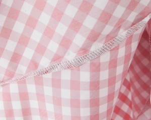 Détail du tissu à carreaux rose et blanc montrant les coutures et la finition de qualité