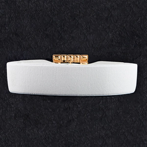 Detailed top view of a white elastic waist belt with gold buckle and amber gems
