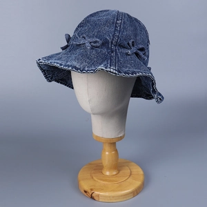 Détail d'un chapeau bob en jean bleu foncé avec volants et nœuds décoratifs
