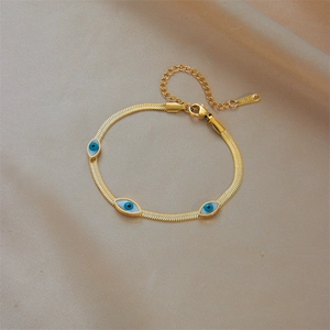 Minimalist gold snake chain bracelet with blue and white evil eye charms on silk