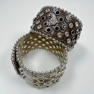 Punk style wide leather bracelets featuring rhinestones and studs on white background
