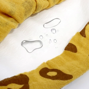 Waterproof cotton baby bib showing liquid droplets on white texture with leopard pattern