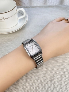 Close-up of a vintage silver square dial watch on wrist with a metal mesh strap