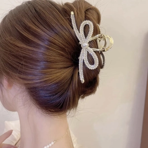 Elegant gold metal bow hair claw clip with pearls and rhinestones on hair