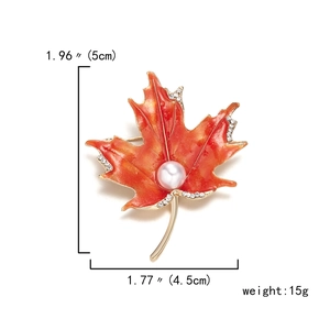 Detail view of maple leaf brooch with dimensions 5cm by 4.5cm and orange enamel finish