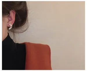 Close-up of crescent zircon stud earrings on model's ear showing elegant curved design