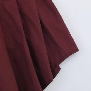 Close-up detail of pleated burgundy poplin shirt fabric with fine stitching and texture