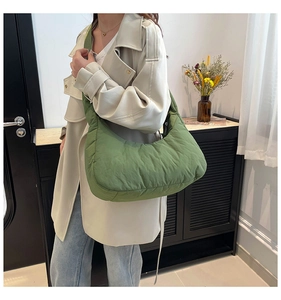Detailed view of a green quilted puffer shoulder bag styled with a neutral autumn coat