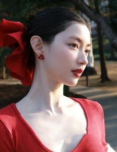 Elegant red berry cluster earrings styled with a large satin bow hair accessory