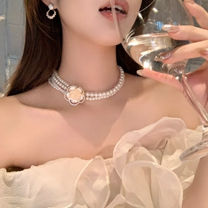 Three-strand resin pearl necklace with a diamond-encrusted floral charm and matching earrings