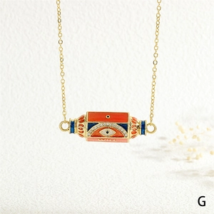 Detail of gold evil eye pendant with WILL engraving and colorful enamel elements