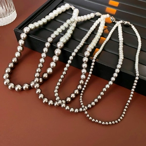 Close-up of pearl necklaces with gradient sizes and colors on a black jewelry stand