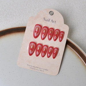 Close-up of red gradient press-on nails with golden cherry patterns and 3D beads