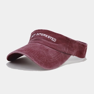 Macro detail of white NOT INTERESTED embroidery on washed dark red visor cap