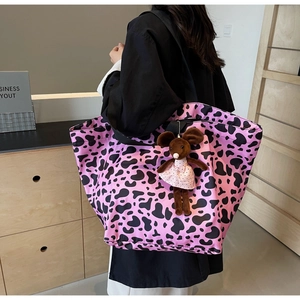 Close-up of pink cow print tote bag with a cute mouse plush charm and wide strap