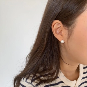 Close-up of minimalist shell-shaped silver earring worn on model for delicate style