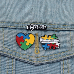 Drie autisme-spelden met hartpuzzel en banner op een blauw spijkerjasje op detail