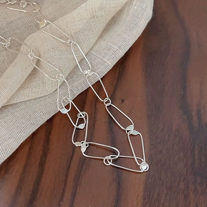 Detailed view of 925 sterling silver long oval link necklace on elegant fabric texture