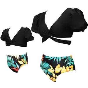 Close-up of matching black puff sleeve bikini sets with vibrant tropical leaf prints