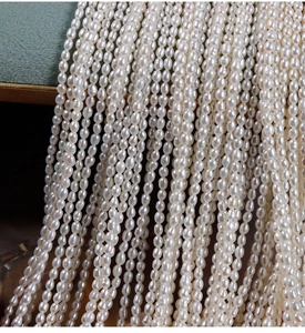 Macro detail of 2.5mm natural freshwater seed pearls on green velvet background