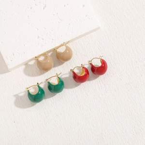 Detail of C-shaped enamel hoop earrings in khaki, red and green with gold metal clasps
