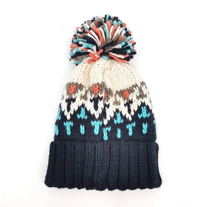 Detailed close-up of heavy knit winter bobble hat with colorful geometric jacquard pattern