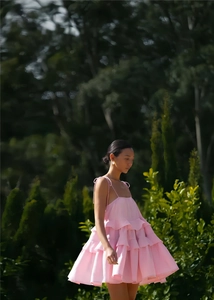 Detail of pink ruffled mini dress with delicate spaghetti straps and layered A-line hem