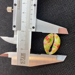 Macro shot showing a 20mm colorful painted seashell bead measured with a digital caliper