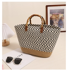 Detail of woven tote bag with bamboo handles and chic pattern on elegant tabletop