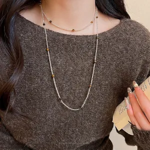 Retro stainless steel beaded necklace with brown tiger eye stones on model in brown sweater