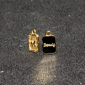 Macro detail of gold butterfly pendant and black Beauty charm on glitter background