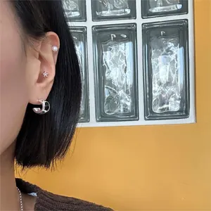 Close-up of S925 silver arc hoop earrings and star studs worn with a pearl ear cuff