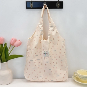 Détail du sac cabas beige gaufré avec motifs d'ours et étiquette de marque tissée