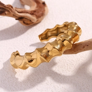 Macro detail of gold spiral bamboo cuff bracelet on driftwood with polished texture