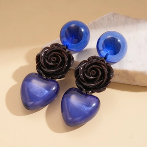 Détail de boucles d'oreilles rétro avec rose sculptée et pendentif cœur bleu œil de chat