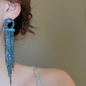 Detail of silver needle geometric tassel earring with blue zircon on model