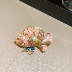 Macro detail of French flower brooch with pink enamel petals, pearl center and crystals