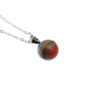 Macro shot of sphere crystal stone pendant with tiger eye texture on silver chain