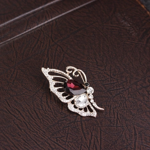 Macro view of butterfly brooch with deep red pear-shaped gemstone and white crystals