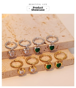 Detailed view of emerald and zircon heart pendants on elegant gold and silver hoops