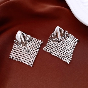 Detail view of silver geometric mesh earrings with square fringe on red silk background