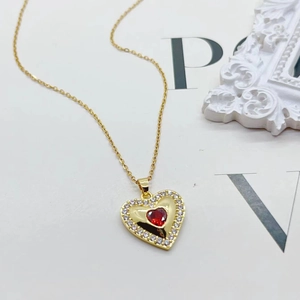Golden necklace with a red heart-shaped gemstone pendant surrounded by white crystals