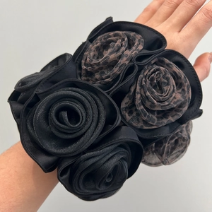Close-up of double-layer satin rose scrunchie in black and leopard print worn on wrist